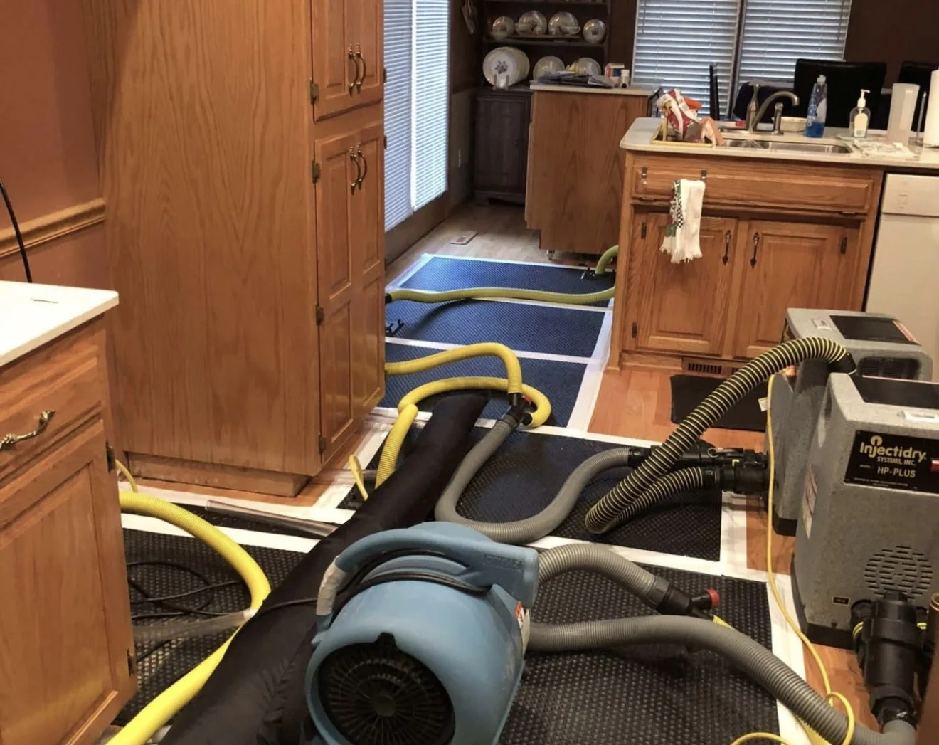 Air movers and a dehumidifier with ducting drying a kitchen after a water loss
