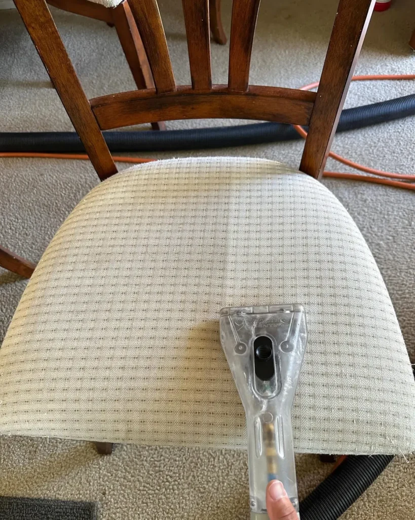 Upholstery tool pulling a clean stripe across a dining chair seat