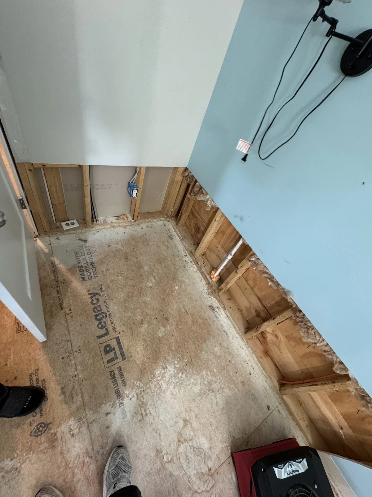 Room with flooring removed and drywall cut away along the bottom after water damage