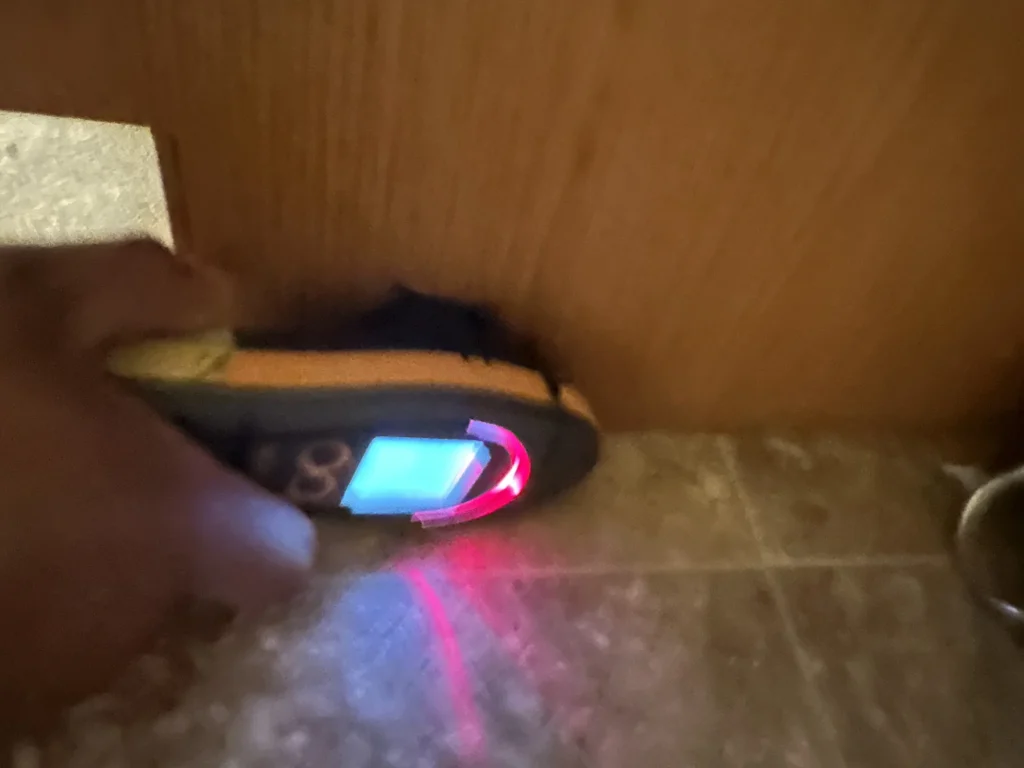 Moisture meter taking a reading on wet carpet beside a wood cabinet
